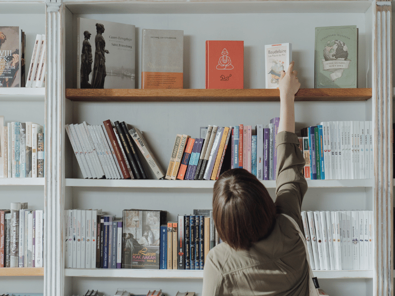 a person reaching for a book on a shelf