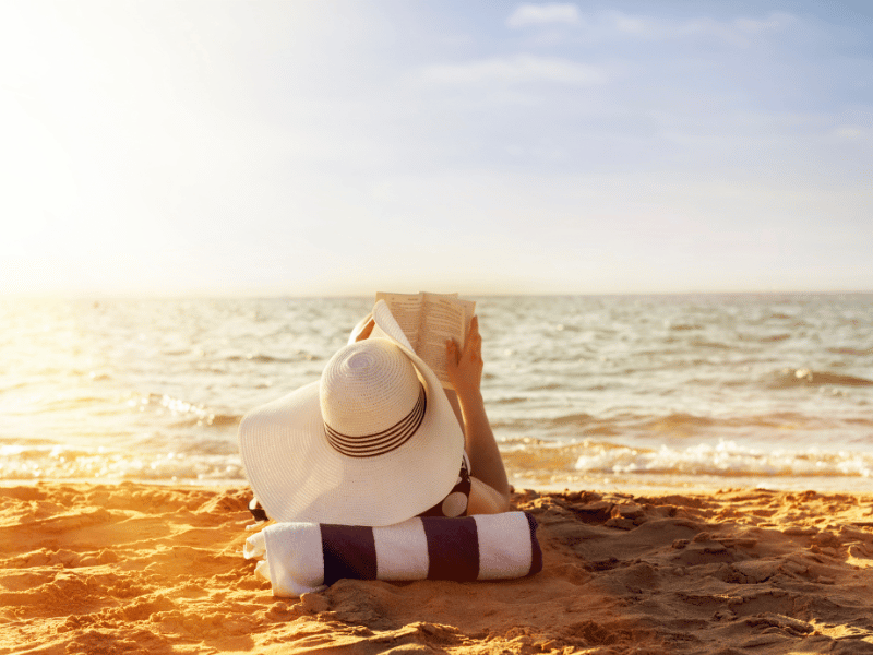 a person reading a book on the beach